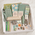 Sage-green stationery gift box in white box showing crossbody ID holder, Notes journal, daisy notebook, lace pencil pouch, pens, correction tape, page flags, butterfly sticky notes, pocket hug, floral tin, clips, washi tape and botanical stickers