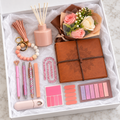 Blush Journal and Diffuser Gift Box – burnt-peach mandala wrap journal, blush reed diffuser, pink and cream rose bouquet, beaded wristlet keychain with tassel, three decorative pens, pink glitter paperclip, correction tape, and sticky note sets arranged in white gift box