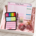 Pastel pink productivity gift box contents in white box with blush tissue paper showing weekly planner, beaded pen, sticky notes, page flags, desk organizer and rhinestone heart keychain